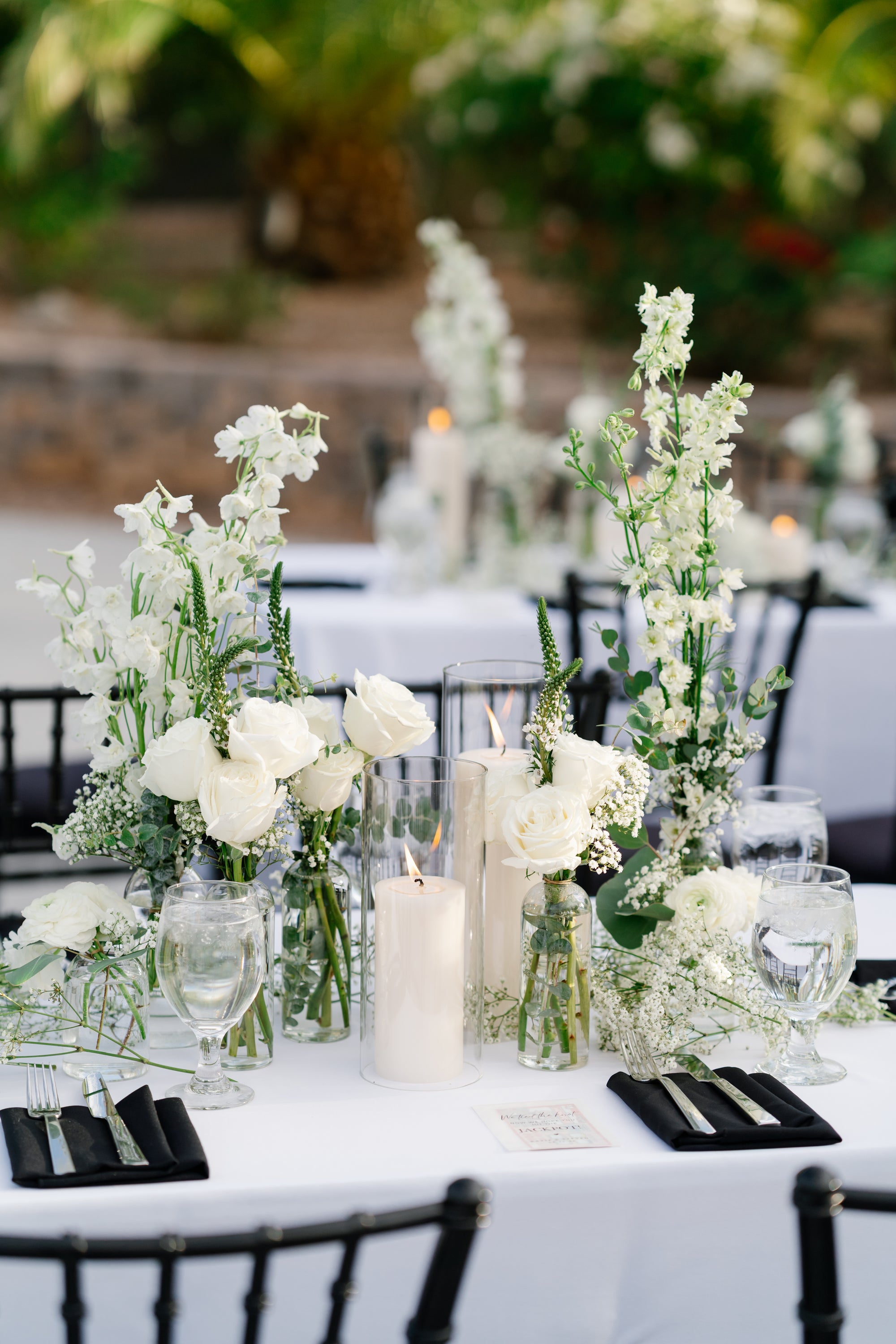 Reception table with white rose and delphinium bud-vase centerpieces and pillar candles