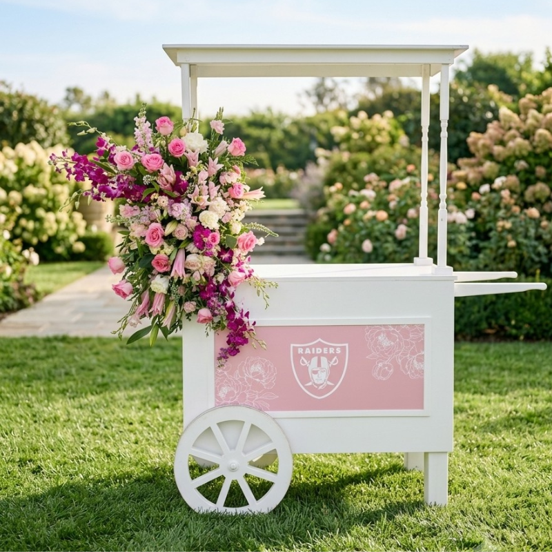 White vintage flower cart decorated with pink and purple floral arrangements featuring a pink Raiders logo.
